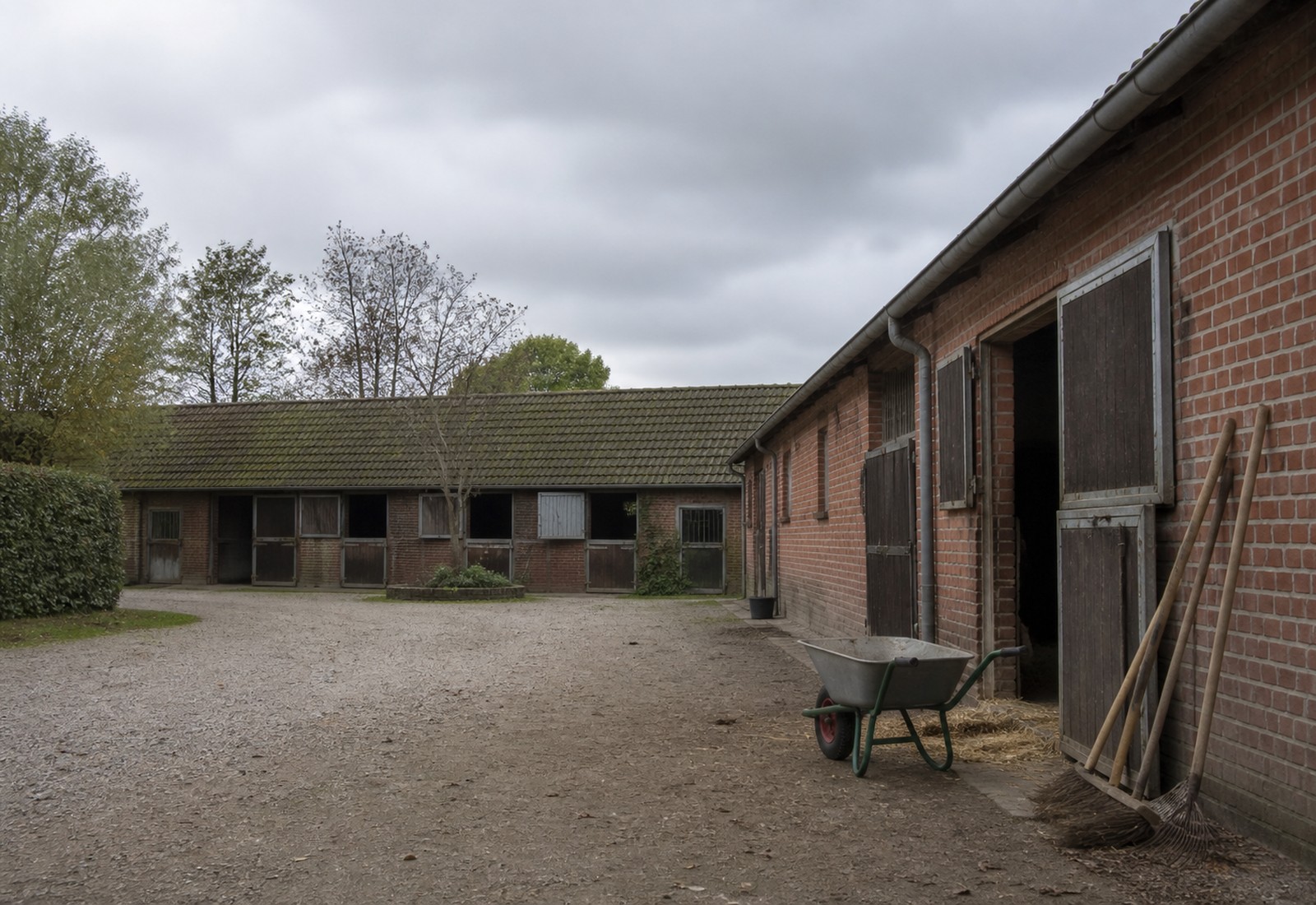 Hofeinfahrt von Reitstall Hasselbrook mit Stallgebäuden und Bäumen
