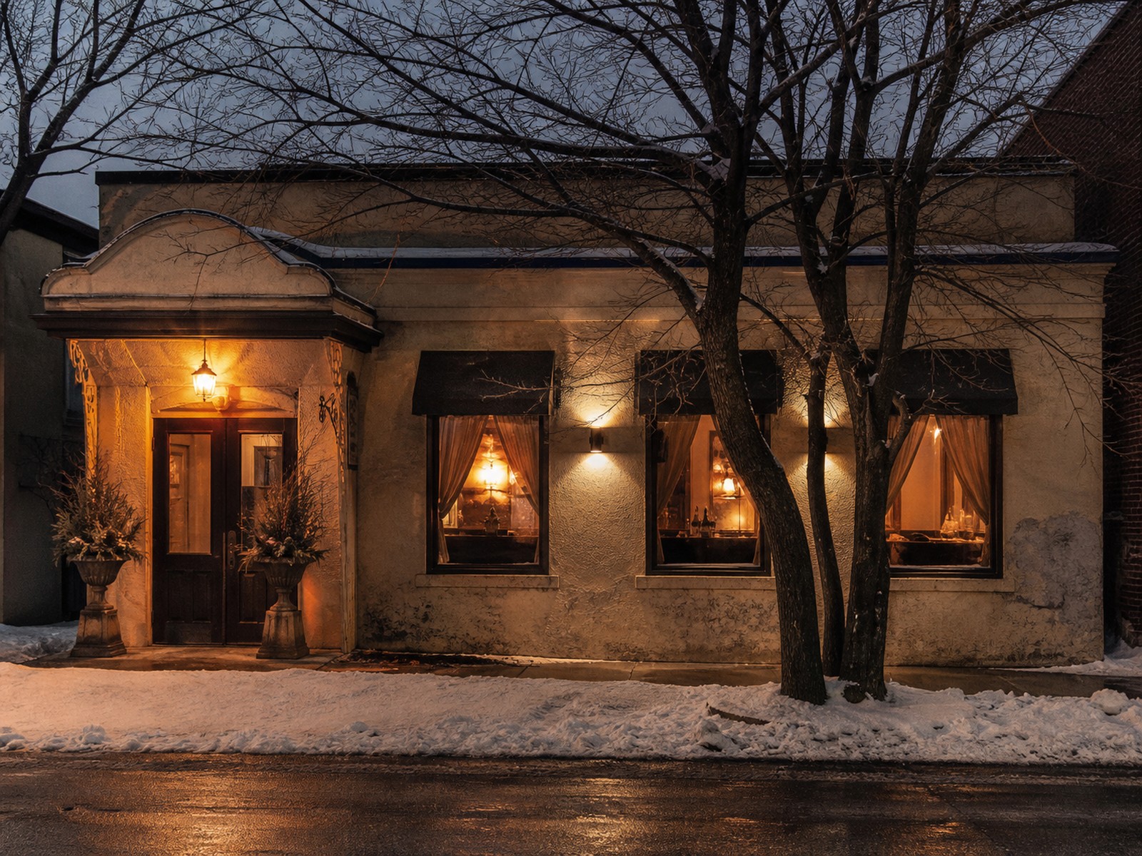Die Trattoria Serafino an einem Winterabend, Licht im Eingang, Schnee davor.